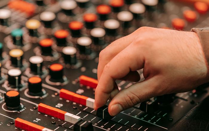Close-up of hands adjusting an audio mixer